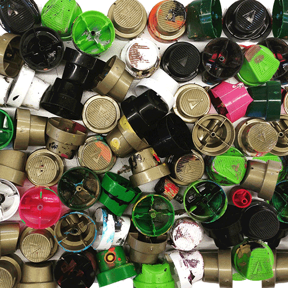 A dense field of used spray can caps, paint-stained, green pink black and gold